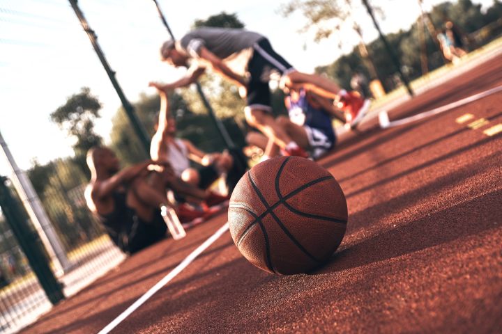 pickup basketball Basketball with basketball players sitting behind it after playing a game.